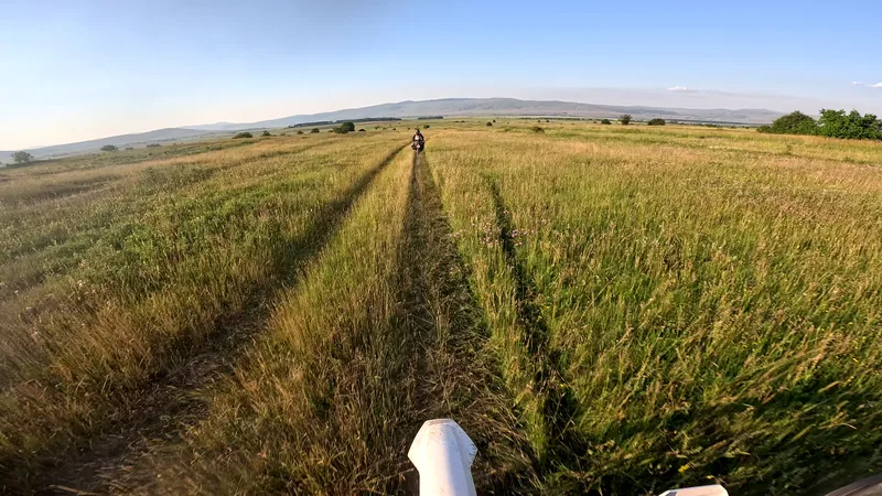 Motorradfahrer auf einer unbefestigten Spur durch bosnische Wiesen